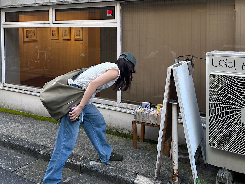 古本屋の前で古本を見る女