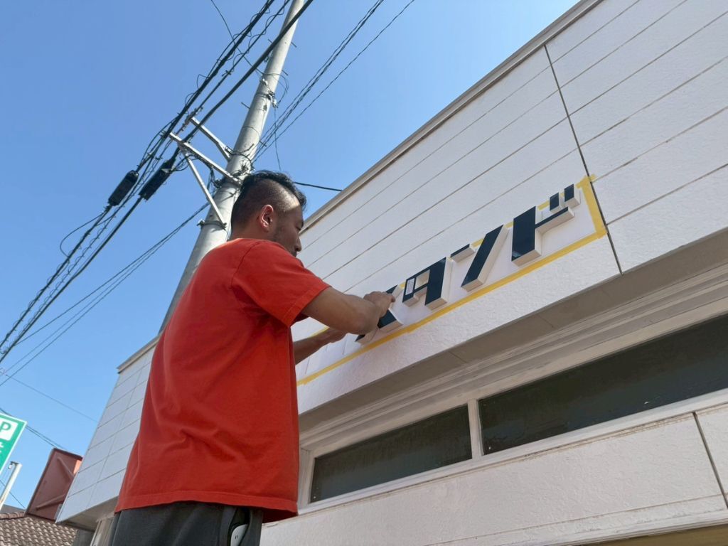 愛媛アカリスタンドの看板取り付け中